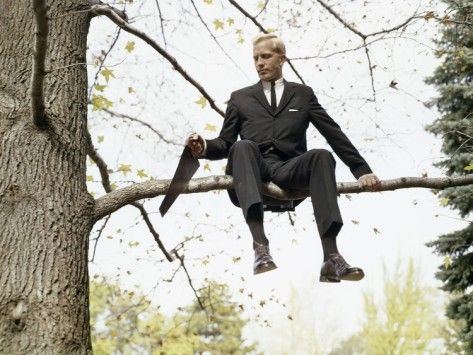 Man in suit on a branch cutting the branch with a saw