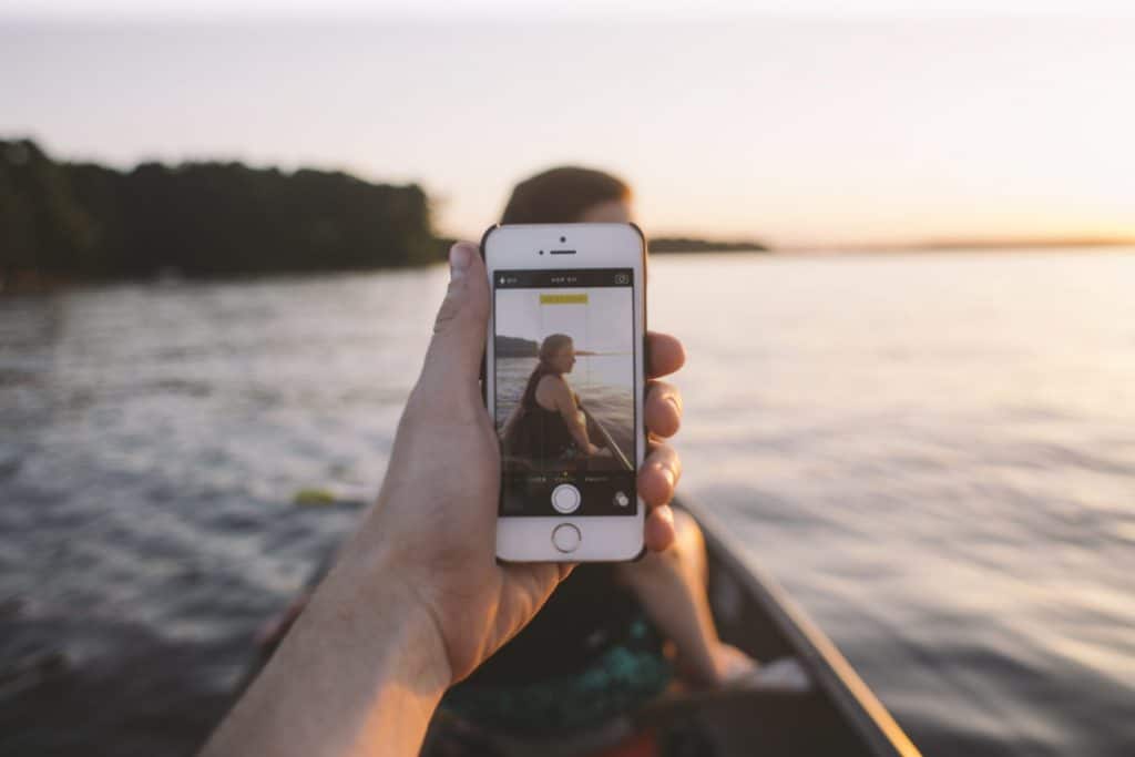 Person holding phone on boat taking photo of person in front of them
