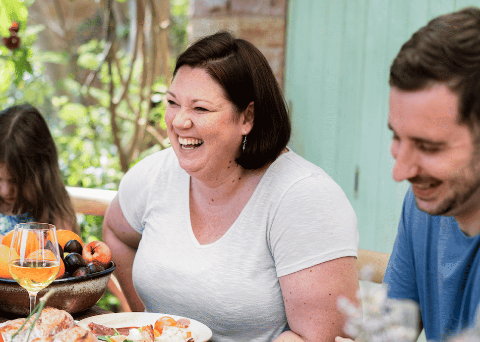 family at dinner table with woman laughing